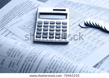 A line of coins and a calculator on business papers
