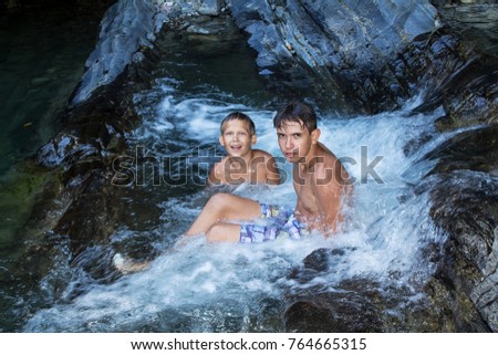 two boys are bathing in a mountain small waterfall