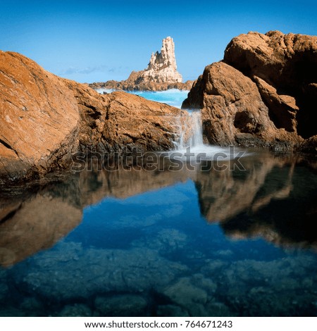 Water flows into a rock ppol at Cala Pregonda, Menorca Royalty-Free Stock Photo #764671243