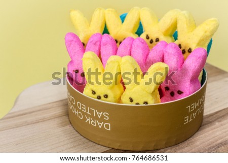 Yellow and pink Peeps on a cutting board.