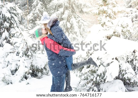 Winter couple playing and have fun in the white snowy forest. Man holding girl face to face. Vertical background for promo banner or advertising for winter holidays or New Year or Christmas.