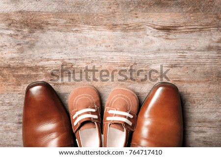 Big and small shoes on wooden background. Father's day composition