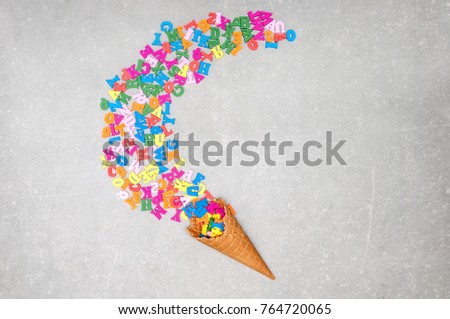 Alphabet letters and ice cream cone on a gray background. Minimalist creative concept. Ice cream cone with letters. Flat lay, top view 