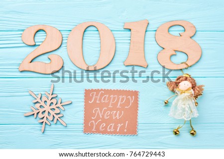 New Year 2018 blue wooden background. Wooden number 2018, wooden cut out snowflake, message and angel figurine on blue wooden background. Happy New Year 2018.