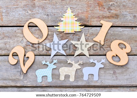 New Year 2018 wooden background. Cut out wooden number 2018, paper figures of Christmas tree, deers and stars on wooden rustic background. Winter handmade craft. Happy New Year 2018.