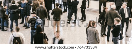 Crowd of anonymous people walking in trade show a hall