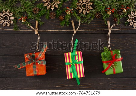 Christmas background with decorations, modern colorful gift boxes on twine rope, garland frame, top view with copy space on wooden table. Winter holidays celebration.