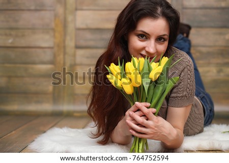 Girl with a bouquet of yellow tulips. Girl with a gift of flowers in a vase. A gift for girls on a female holiday with yellow tulips on floor.