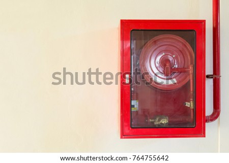 Fire extinguisher and fire hose reel on concrete wall. copy space