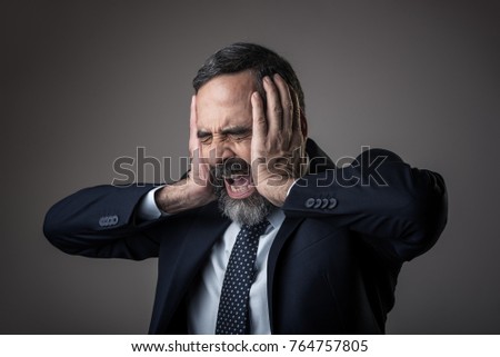 Senior business man having a terrible headache, screaming furiously Royalty-Free Stock Photo #764757805