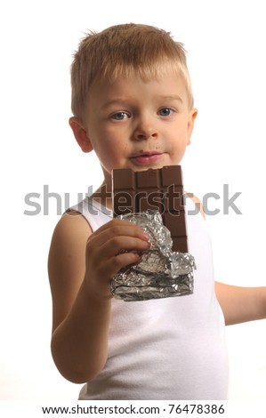 Picture of a little blond boy in white top eating chocolate
