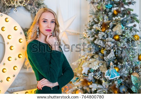 Beautiful young girl in a green dress in a christmas interior