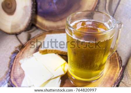 Beer in glass mug & cheese with bread, on wooden background