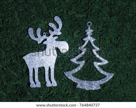 Silver toy Christmas tree and elk on the moss background