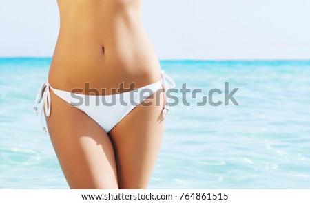 Body part of slim and sporty young girl over ocean background. Traveling and vacation concept.