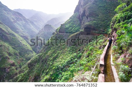 An old aqueduct now used as an adventure hiking trail in the Anaga Mountains, Tenerife, Spain Royalty-Free Stock Photo #764871352