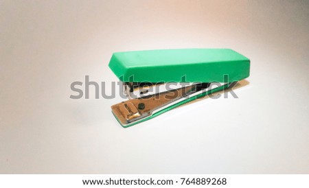 One green stapler on the white floor