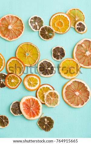 Top view on sliced dried citrus chips: orange, lemon and grapefruit on turquoise wooden background.