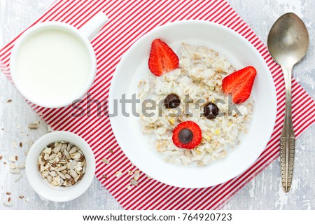Fun and healthy breakfast idea for kids - sweet oatmeal porridge bowl with strawberry and chocolate