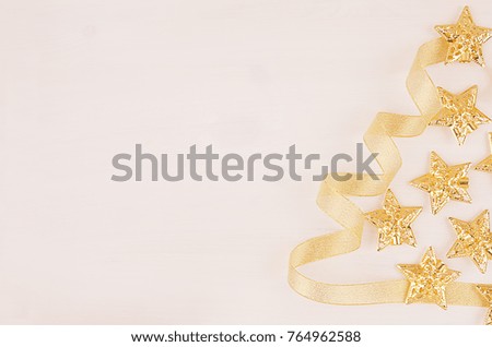 Half christmas tree of gold stars, balls, curl ribbons on soft white wood board, top view, copy space.