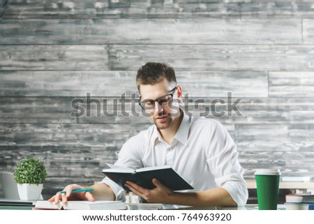 European businessman reading books at workplace. Knowledge and education concept 