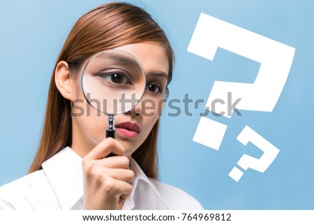 Young woman looking through a magnifying glass. 
