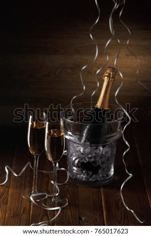 Photo of two glasses, bucket of ice and bottle of wine