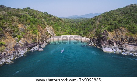 Secret beach Butterfly in Goa, India. Aerial view of pristine beach with rocky bay and waves crashing Royalty-Free Stock Photo #765055885