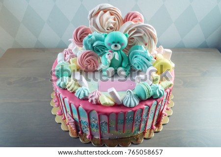 Big beautiful kids cake decorated with turquoise Teddy bear and colorful meringues and marshmallows. The concept of festive desserts for the birthday children