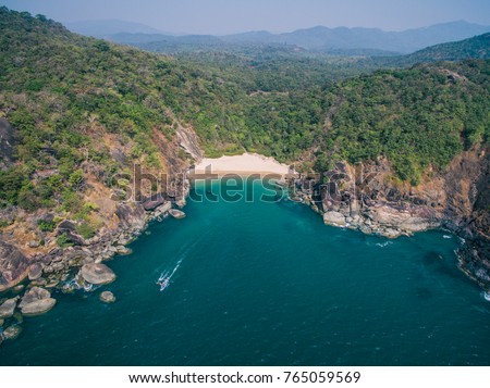 Beautiful secret beach Butterfly in Goa, India. Aerial view of pristine beach with rocky bay and waves crashing Royalty-Free Stock Photo #765059569