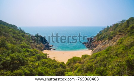 Beautiful secret beach Butterfly in Goa, India. Aerial view of pristine beach with rocky bay and waves crashing Royalty-Free Stock Photo #765060403