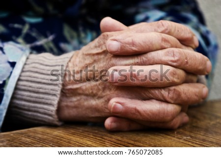 The old grandmother put wrinkled hands on a wooden table
