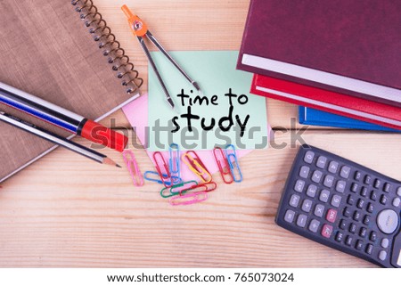 Memo with handwriting written as time to study on wooden background with stationary and books. Top view composition