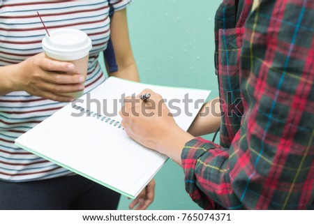 Education concept. Two Asian women one student or roommate with friend 
helps analyzing workbook learning outdoor , Tutor books with friends.On green background.Selective focus