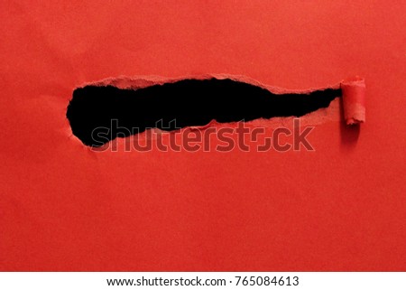 Closeup of black hole on red paper.
