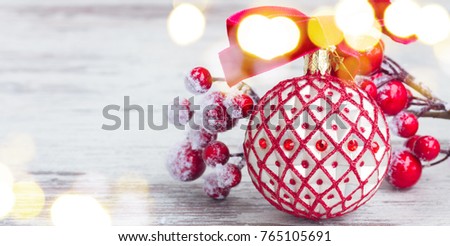 red an white christmas - ball and twig with frosted berries clos eup on aged wooden background