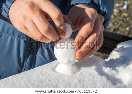 Male hands sculpting from the snow small snowballs that would make a snowman