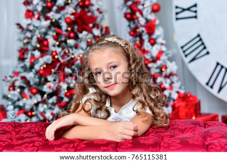 little girl in white dress with Christmas gift sitting near Christmas tree, a nice smile