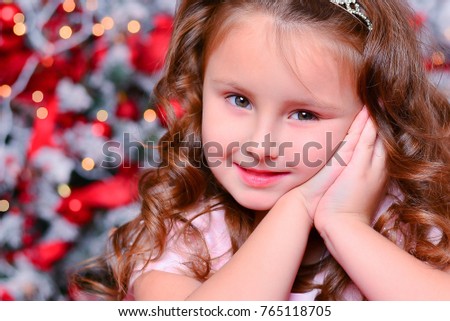 little girl in pink dress with Christmas gift sitting near Christmas tree, a nice smile
