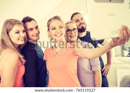 Fun bonding selfie concept. Group of diverse friends students classmates taking self photo with tablet pc computer indoors in class
