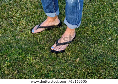 Female in flip flops walking across grass field