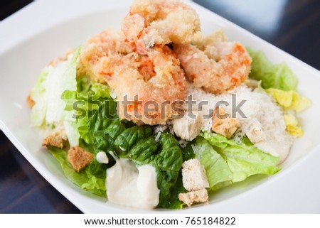 Classical Caesar salad with tempura shrimp on a plate