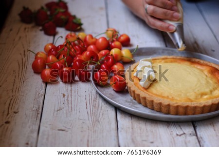 A woman  making  delicious tart with berries for her family on holiday.Image of female hands decoration a cake with pastry decorating bag.