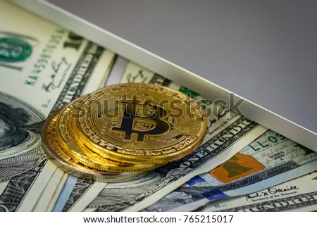 Bitcoin golden coins on a dollar banknotes office background  white laptop mobile