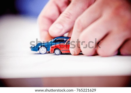 Blue and red toy cars are pushed on a table during a meeting.  Concept for car insurance, road safety, traffic conditions, road planning, and business meetings.