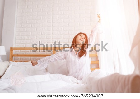 Beautiful smilling woman waking up in her bed in the bedroom, she is stretching and smiling in early morning. Royalty-Free Stock Photo #765234907