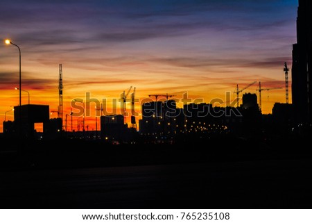 Tower cranes on construction site in sunset. Buildings under construction in sunrise. City skyline silhouette illustration.
