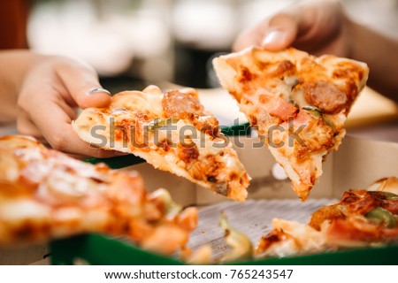 Asian students eating eating the pizza together in breaking time early next study class having fun and enjoy party, Italian food slice with cheese delicious at university outdoor. Royalty-Free Stock Photo #765243547