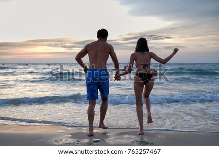 Asian lovers hand in hand running on the sea