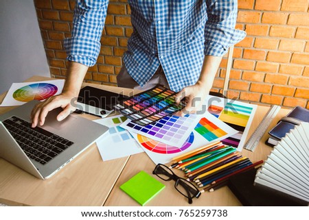 Designer graphic creative ,Man in blue shirt Working on laptop in  office with sunset background,Selective focus.